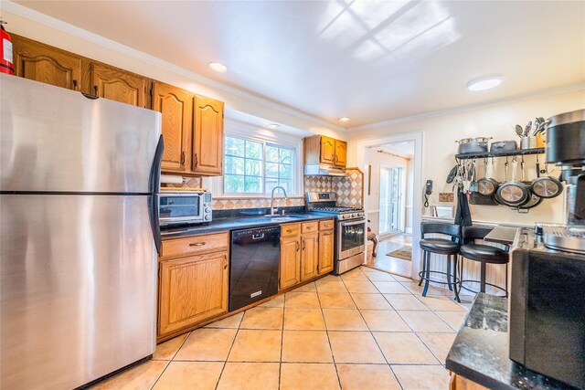 5 Cary Rd, Great Neck, NY 11021 - kitchen with appliances with stainless steel finishes, under cabinet range hood, dark countertops, crown molding, and light tile patterned floors