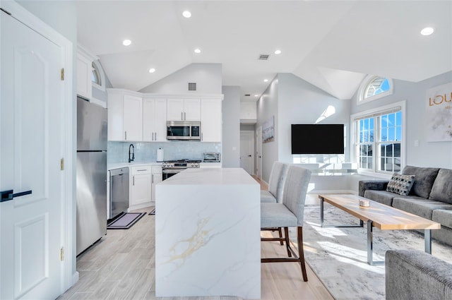 68 Brookline Ave, East Atlantic Beach, NY 11561 - kitchen featuring stainless steel appliances, open floor plan, lofted ceiling, a center island, and white cabinetry
