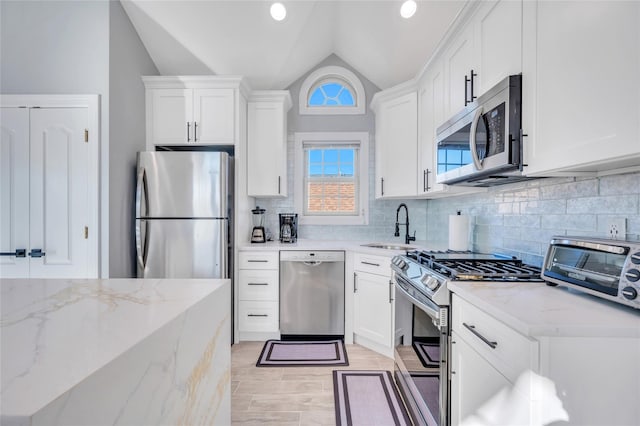 68 Brookline Ave, East Atlantic Beach, NY 11561 - kitchen with stainless steel appliances, a sink, vaulted ceiling, white cabinets, and recessed lighting