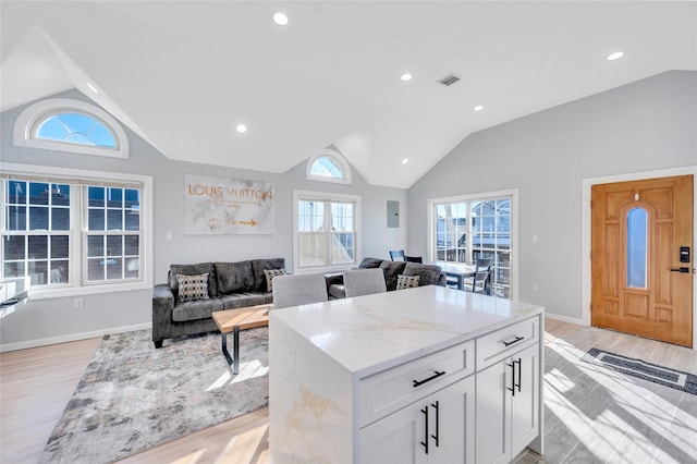68 Brookline Ave, East Atlantic Beach, NY 11561 - kitchen featuring lofted ceiling, light wood finished floors, white cabinets, light stone countertops, and open floor plan