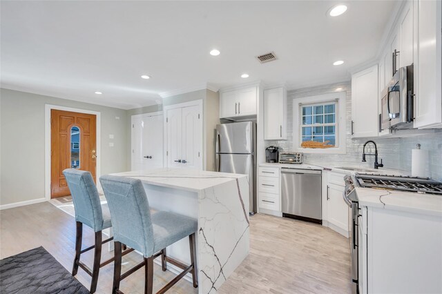 68 Brookline Ave, East Atlantic Beach, NY 11561 - kitchen featuring stainless steel appliances, a kitchen island, a sink, tasteful backsplash, and light wood-style flooring