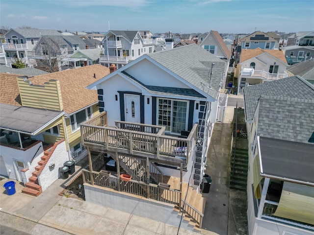 68 Brookline Ave, East Atlantic Beach, NY 11561 - view of front of house with stairs, a residential view, a shingled roof, a wooden deck, and stucco siding
