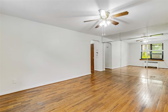 22-39 78th St Unit 2F, East Elmhurst, NY 11370 - unfurnished room with radiator heating unit, hardwood / wood-style flooring, arched walkways, a ceiling fan, and cooling unit