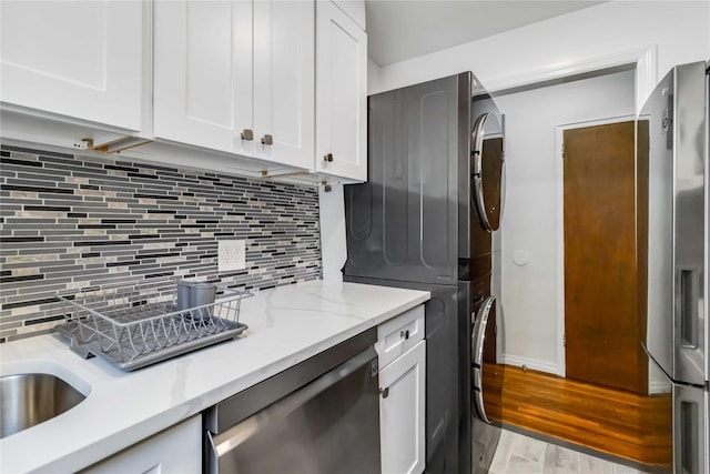 22-39 78th St Unit 2F, East Elmhurst, NY 11370 - kitchen with estacked washer and dryer, stainless steel appliances, white cabinets, and backsplash