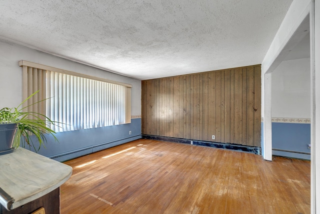 34 Leeside Dr, Carmel, NY 10512 - empty room with baseboard heating, wood finished floors, wooden walls, a textured ceiling, and baseboards
