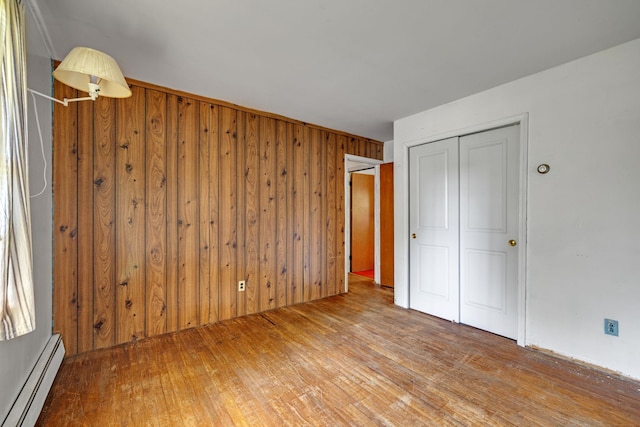 34 Leeside Dr, Carmel, NY 10512 - unfurnished bedroom with a baseboard heating unit, wood finished floors, wood walls, and a closet