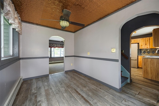 13 Cedar Ln, Poughkeepsie, NY 12601 - empty room featuring a baseboard heating unit, arched walkways, a ceiling fan, wood finished floors, and an ornate ceiling