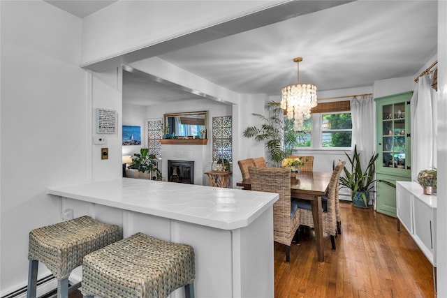 123 Maple Ave, Northport, NY 11768 - kitchen with a chandelier, dark wood-style floors, a peninsula, a brick fireplace, and light countertops