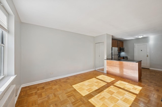 162-21 Powells Cove Blvd Unit 1M, Beechhurst, NY 11357 - kitchen with stainless steel appliances, radiator, baseboards, dark countertops, and a peninsula