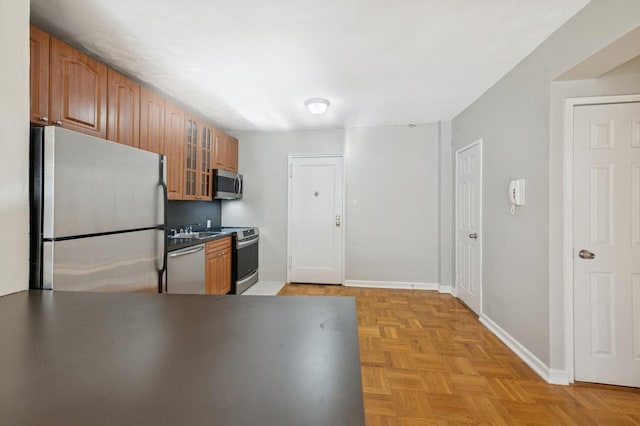 162-21 Powells Cove Blvd Unit 1M, Beechhurst, NY 11357 - kitchen with appliances with stainless steel finishes, a sink, glass insert cabinets, baseboards, and brown cabinetry