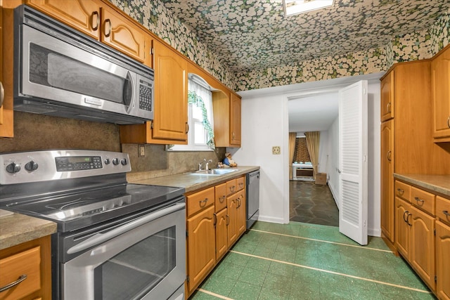 725 Clinton St, Westbury, NY 11590 - kitchen featuring appliances with stainless steel finishes, decorative backsplash, a sink, brown cabinets, and baseboards