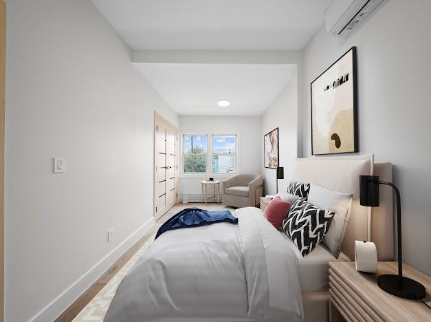 14-09 131st St, College Point, NY 11356 - bedroom featuring baseboards, a wall unit AC, wood finished floors, and baseboard heating