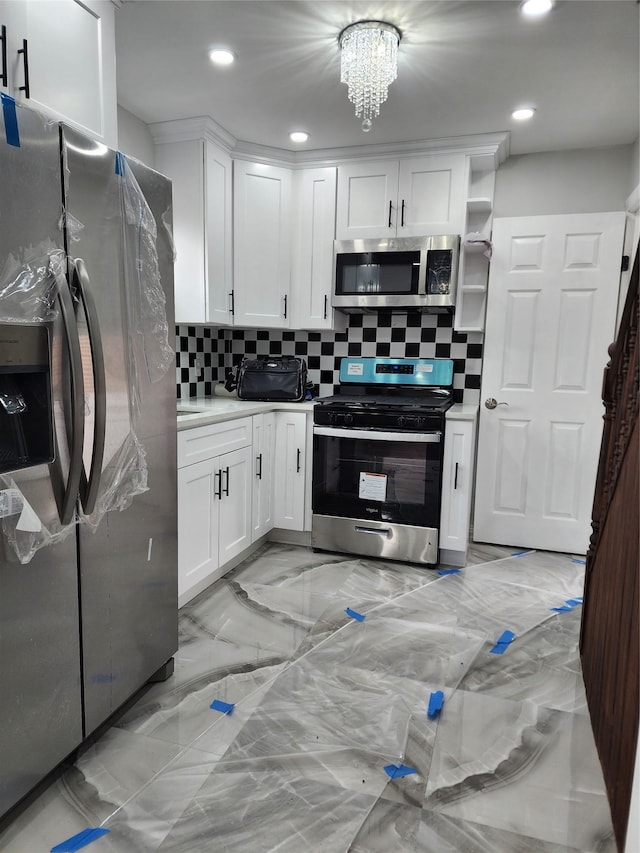 224-06 114th Rd, Cambria Heights, NY 11411 - kitchen featuring stainless steel appliances, decorative backsplash, white cabinets, light countertops, and light marble finish flooring