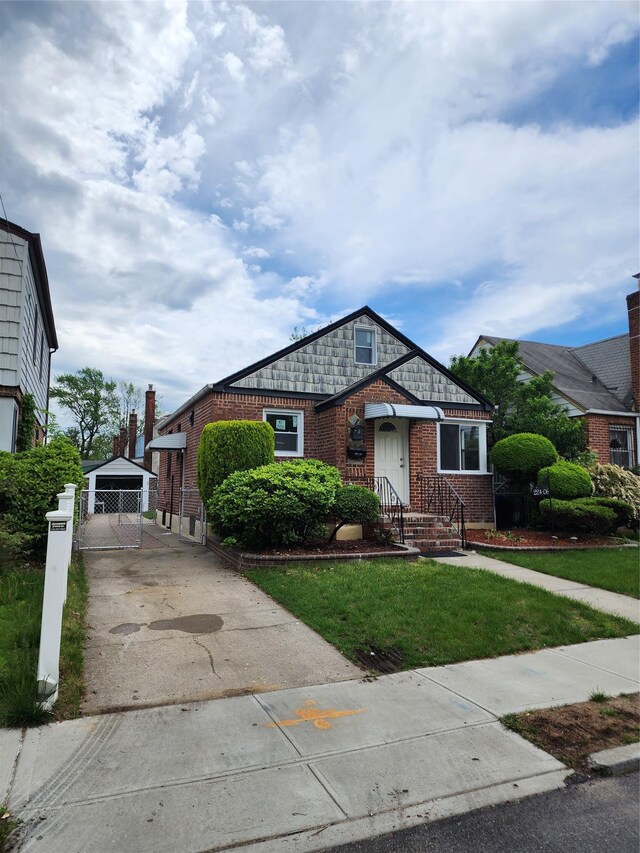 224-06 114th Rd, Cambria Heights, NY 11411 - view of front facade featuring brick siding, a front lawn, and an outbuilding