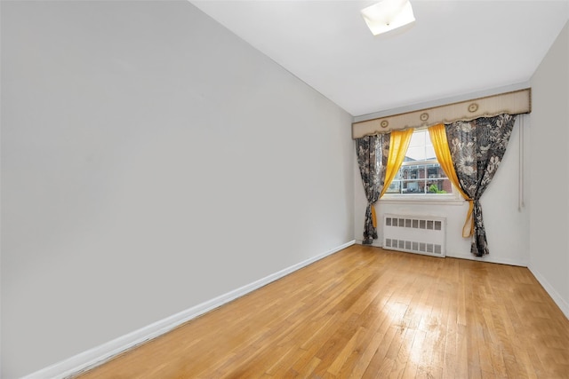 7345 53rd Rd, Maspeth, NY 11378 - spare room with radiator, light wood-style flooring, and baseboards