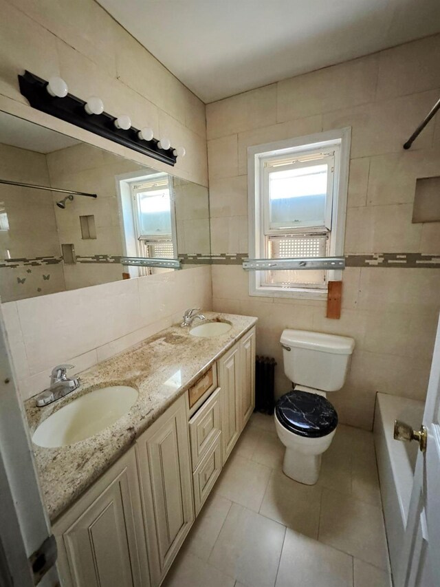 186-39 Ilion Ave, Saint Albans, NY 11412 - full bathroom with toilet, tile walls, double vanity, tile patterned floors, and washtub / shower combination