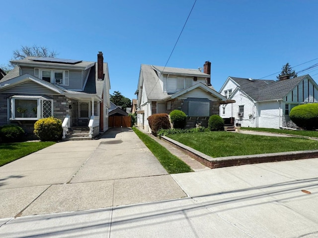 186-39 Ilion Ave, Saint Albans, NY 11412 - bungalow-style home featuring roof mounted solar panels, a front lawn, concrete driveway, and a chimney
