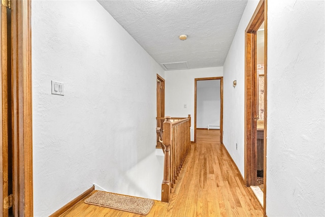 123 Birch Ln, New City, NY 10956 - corridor with an upstairs landing, light wood-style flooring, a baseboard heating unit, a textured wall, and a textured ceiling