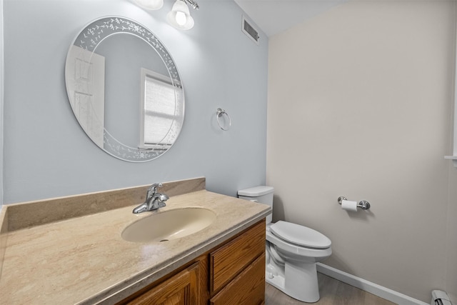 7 Brandy Ln, Hopewell Junction, NY 12590 - half bath featuring a baseboard radiator, toilet, vanity, wood finished floors, and baseboards