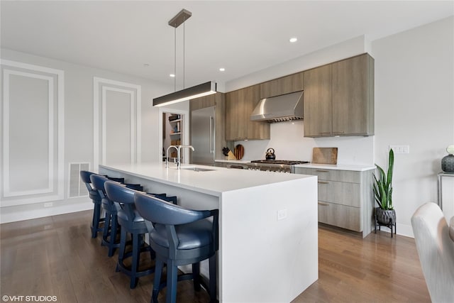 18 Rose Ln, Rye Brook, NY 10573 - kitchen with range hood, modern cabinets, a sink, a breakfast bar, and light countertops