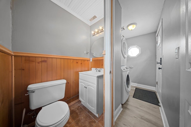 199 Central Ave, Bethpage, NY 11714 - bathroom with stacked washing machine and dryer, toilet, wainscoting, ornamental molding, and vanity