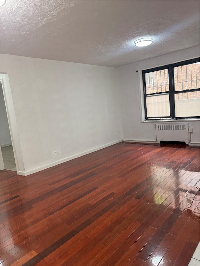 44-11 Macnish St Unit 1E, Elmhurst, NY 11373 - unfurnished room with radiator heating unit, hardwood / wood-style flooring, a textured ceiling, and baseboards