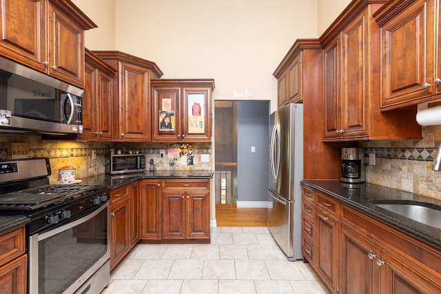 449 Terry Blvd, Holbrook, NY 11741 - kitchen with appliances with stainless steel finishes, backsplash, dark stone countertops, a sink, and brown cabinets