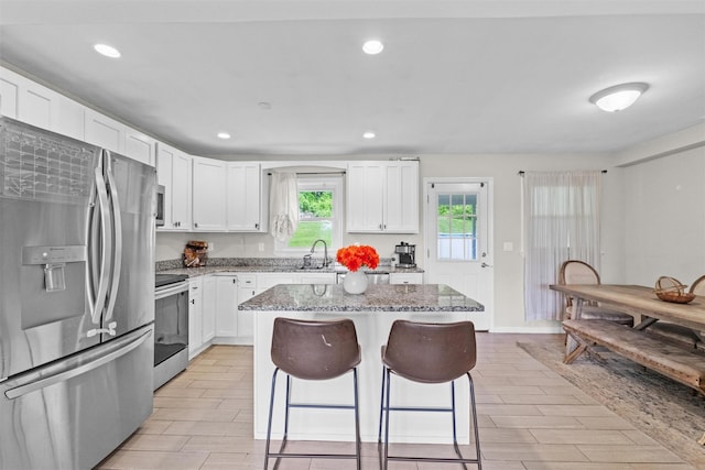 3518 Overlook Ave, Yorktown Heights, NY 10598 - kitchen featuring appliances with stainless steel finishes, a kitchen bar, light stone counters, a sink, and a center island