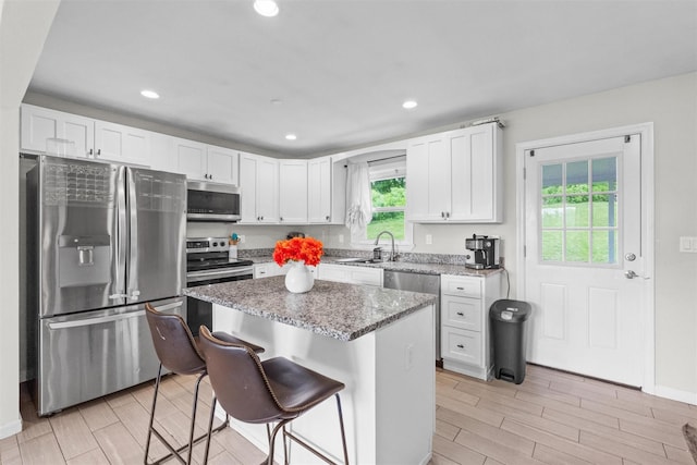 3518 Overlook Ave, Yorktown Heights, NY 10598 - kitchen featuring appliances with stainless steel finishes, a kitchen breakfast bar, light stone counters, wood finish floors, and a sink
