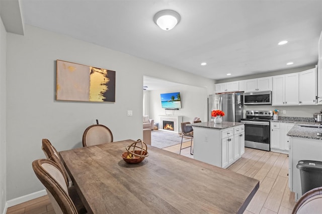 3518 Overlook Ave, Yorktown Heights, NY 10598 - dining space with a warm lit fireplace, light wood finished floors, recessed lighting, and baseboards