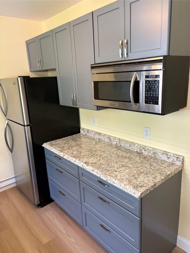 4279 Oneida Ave, Bronx, NY 10470 - kitchen with appliances with stainless steel finishes, light wood-style floors, gray cabinetry, and baseboards