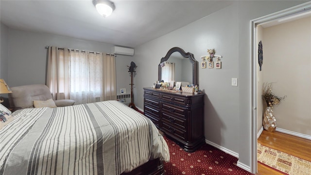 30-33 79th St, East Elmhurst, NY 11370 - bedroom featuring baseboards, a wall mounted air conditioner, and wood finished floors