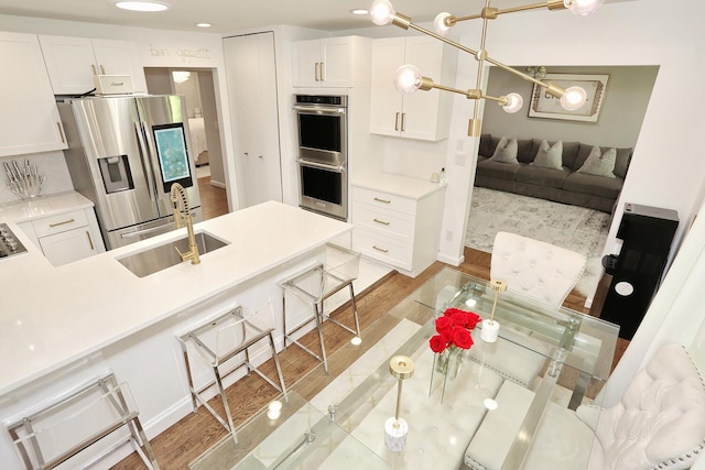 100 Dowd St Unit C12, Haverstraw, NY 10927 - kitchen with stainless steel appliances, a sink, white cabinetry, a breakfast bar, and light wood finished floors