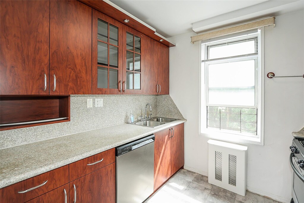 7445 Yellowstone Blvd Unit 5C, Rego Park, NY 11374 - kitchen with stainless steel appliances, a sink, tasteful backsplash, and glass insert cabinets