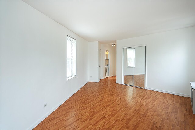 7445 Yellowstone Blvd Unit 5C, Rego Park, NY 11374 - unfurnished bedroom with light wood-type flooring, multiple windows, and baseboards