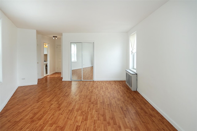 7445 Yellowstone Blvd Unit 5C, Rego Park, NY 11374 - unfurnished bedroom with light wood finished floors, multiple windows, and baseboards