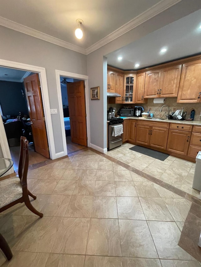 108-41 51st Ave, Corona, NY 11368 - kitchen with stainless steel range with gas stovetop, crown molding, brown cabinets, baseboards, and under cabinet range hood