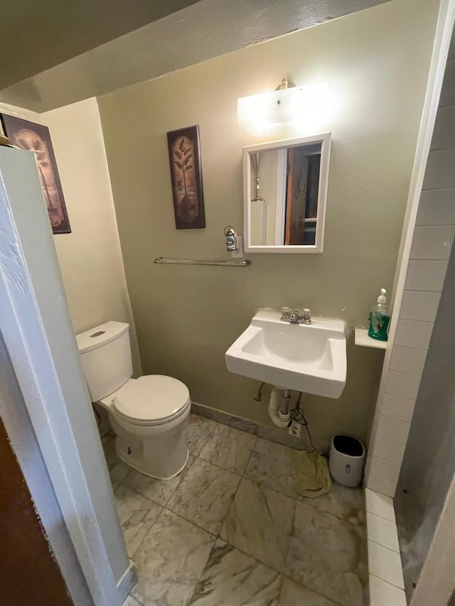 108-41 51st Ave, Corona, NY 11368 - bathroom with marble look tile flooring, toilet, baseboards, and a sink