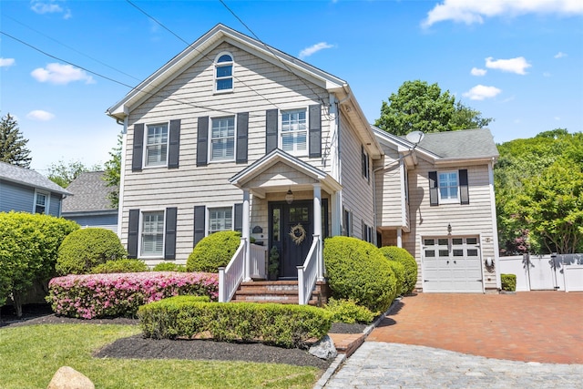 view of front of home with decorative driveway, an attached garage, and a gate