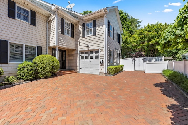 view of front of home featuring decorative driveway, a garage, and a gate