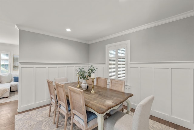 dining area with a decorative wall, ornamental molding, wainscoting, wood finished floors, and recessed lighting