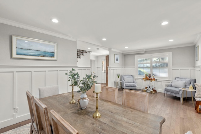 dining room with a decorative wall, ornamental molding, wainscoting, light wood finished floors, and recessed lighting