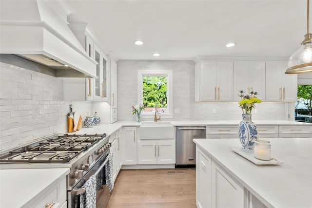 kitchen featuring stainless steel appliances, custom range hood, plenty of natural light, light countertops, and recessed lighting