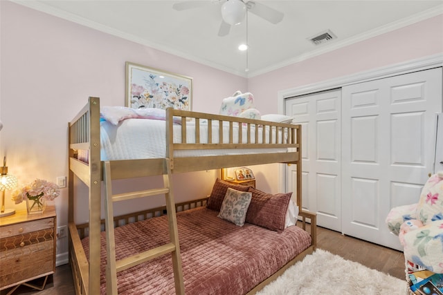 bedroom with a closet, wood finished floors, ornamental molding, and ceiling fan