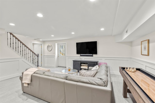 living area featuring a decorative wall, stairs, recessed lighting, and wainscoting