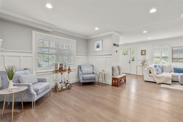 sitting room with a decorative wall, crown molding, light wood-style flooring, recessed lighting, and wainscoting
