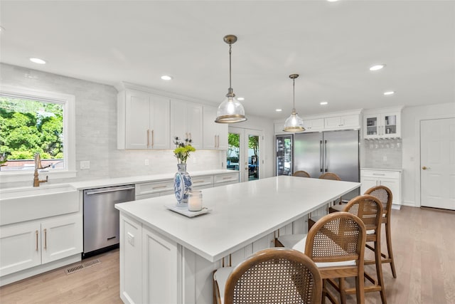kitchen featuring dishwasher, a sink, tasteful backsplash, white cabinetry, and recessed lighting