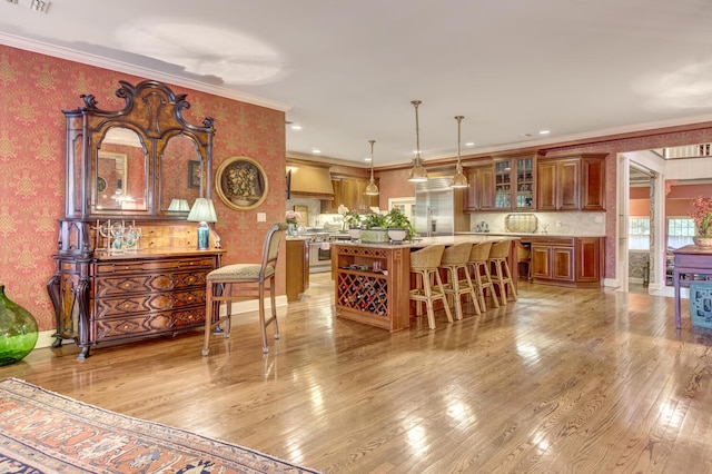 7 Cedar Ln, Glen Cove, NY 11542 - kitchen featuring wallpapered walls, premium appliances, custom exhaust hood, brown cabinetry, and light wood finished floors