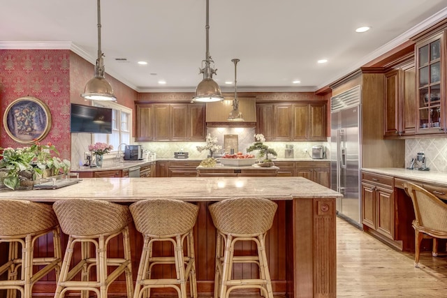 7 Cedar Ln, Glen Cove, NY 11542 - kitchen with stainless steel built in fridge, backsplash, glass insert cabinets, light stone counters, and a breakfast bar