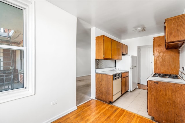 34-43 60th St Unit 4J, Woodside, NY 11377 - kitchen with dishwasher, light countertops, brown cabinets, gas cooktop, and freestanding refrigerator